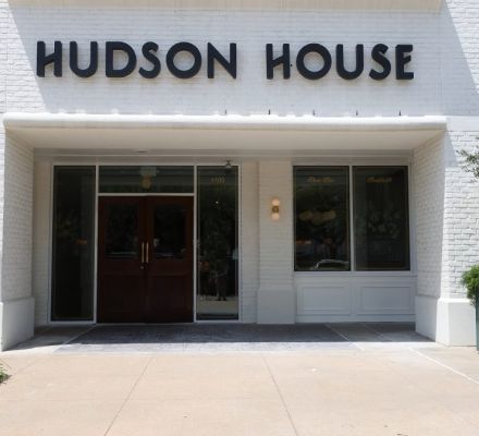 Hudson House storefront entrance with wooden doors and white brick facade.